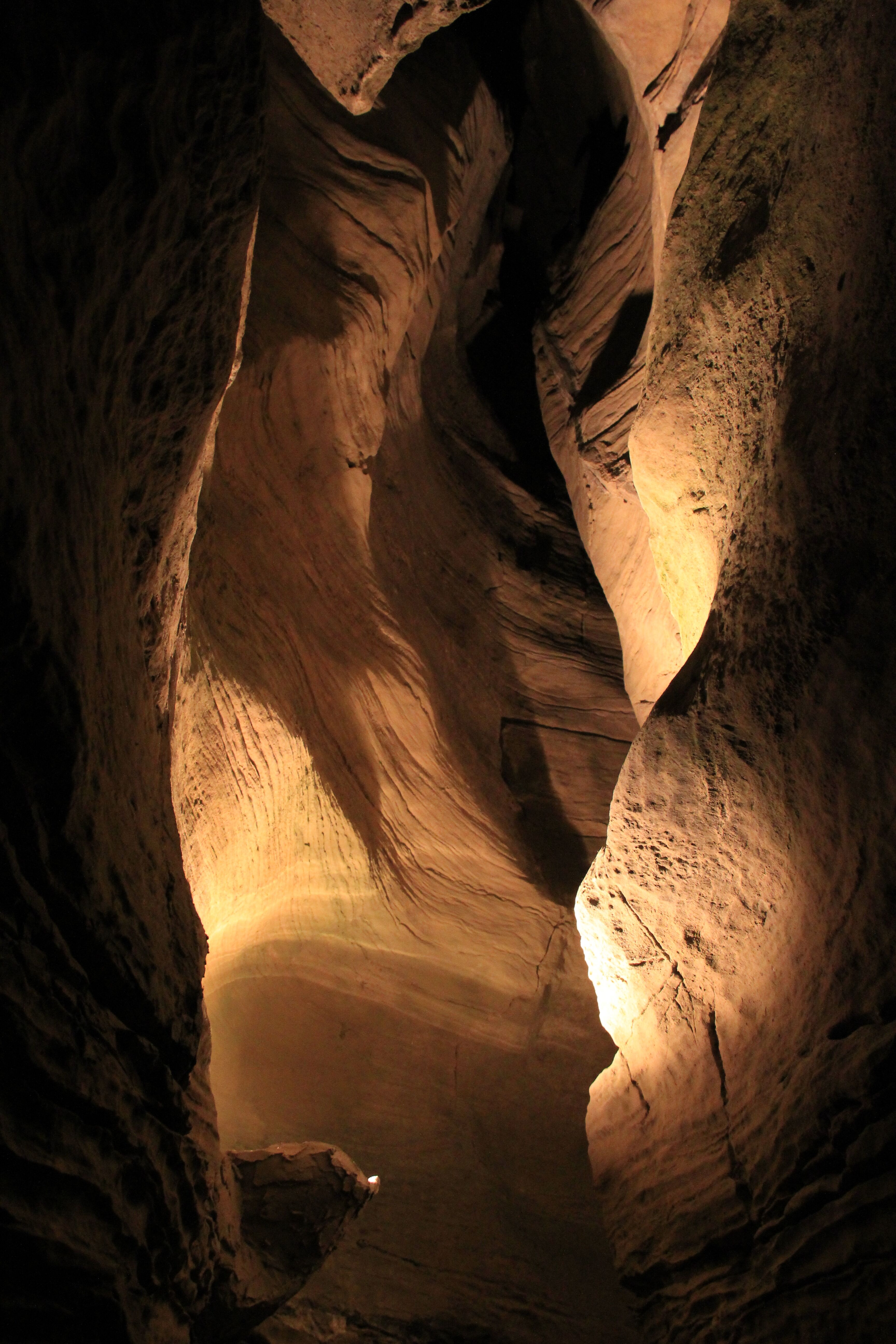 Lantern-lit limestone passage with sculpted, swirling walls inside Howe Caverns